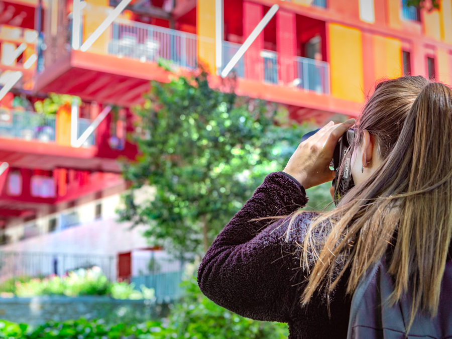 jeune femme photographie un bâtiment rouge