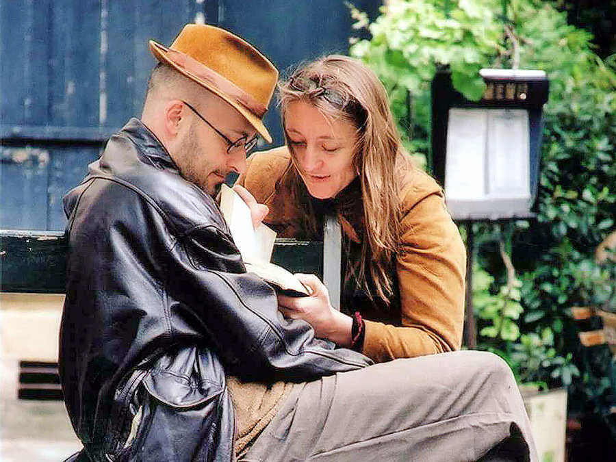 un couple lit un livre sur un banc à Paris